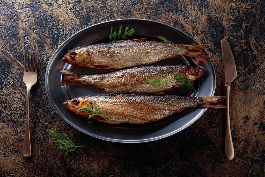 Three Grilled Whole Herring Fillets On a Plate.