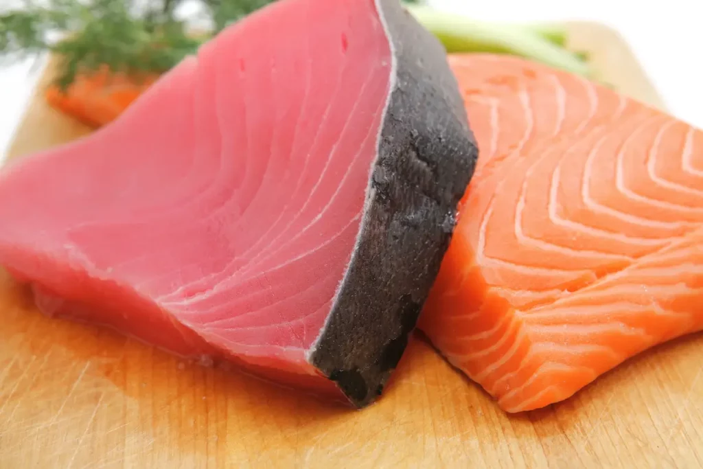 Pieces of fresh, raw salmon and tuna on a wooden board.